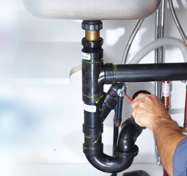 Plumbing under a sink being worked on